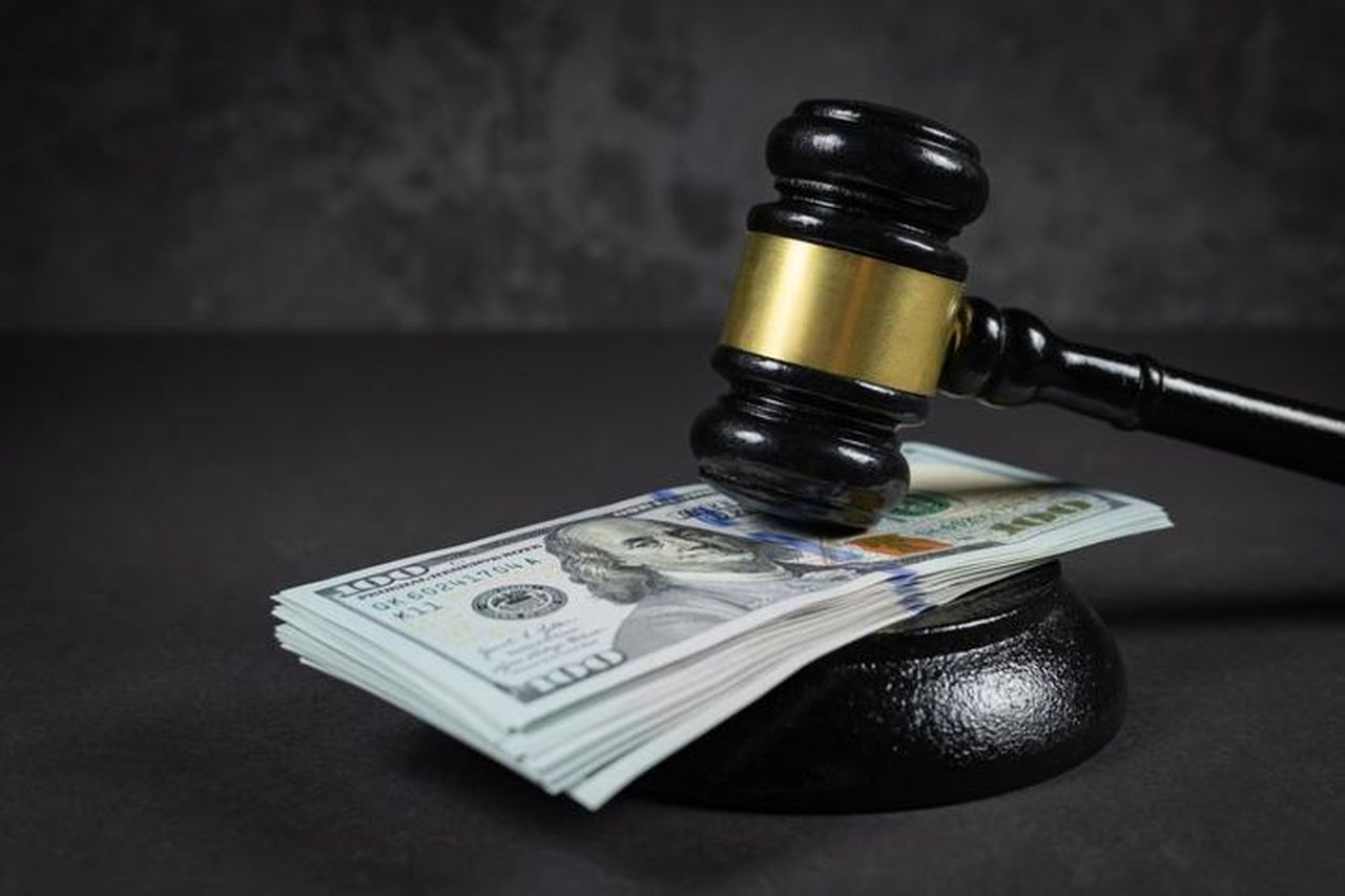 Il_risarcimento_per_lattacco_razzista_Q3RYocLFqv - Confidenze24 source:bossip - Il risarcimento per l'attacco razzista - Concetto di legge e giustizia. Martello del giudice con il dollaro posato - concetto di giudizio e giustizia. Riguardo a frodi fiscali e multe.