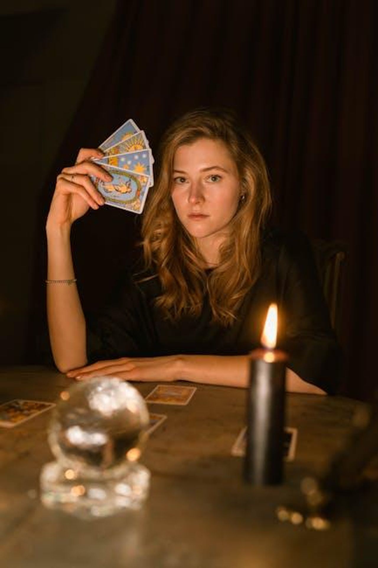 11_Ariete_aqUfGPFnxd - Confidenze24 Source: Anastasia Shuraeva - pexels - A woman in a dark room predicting the future with tarot cards and a candle.