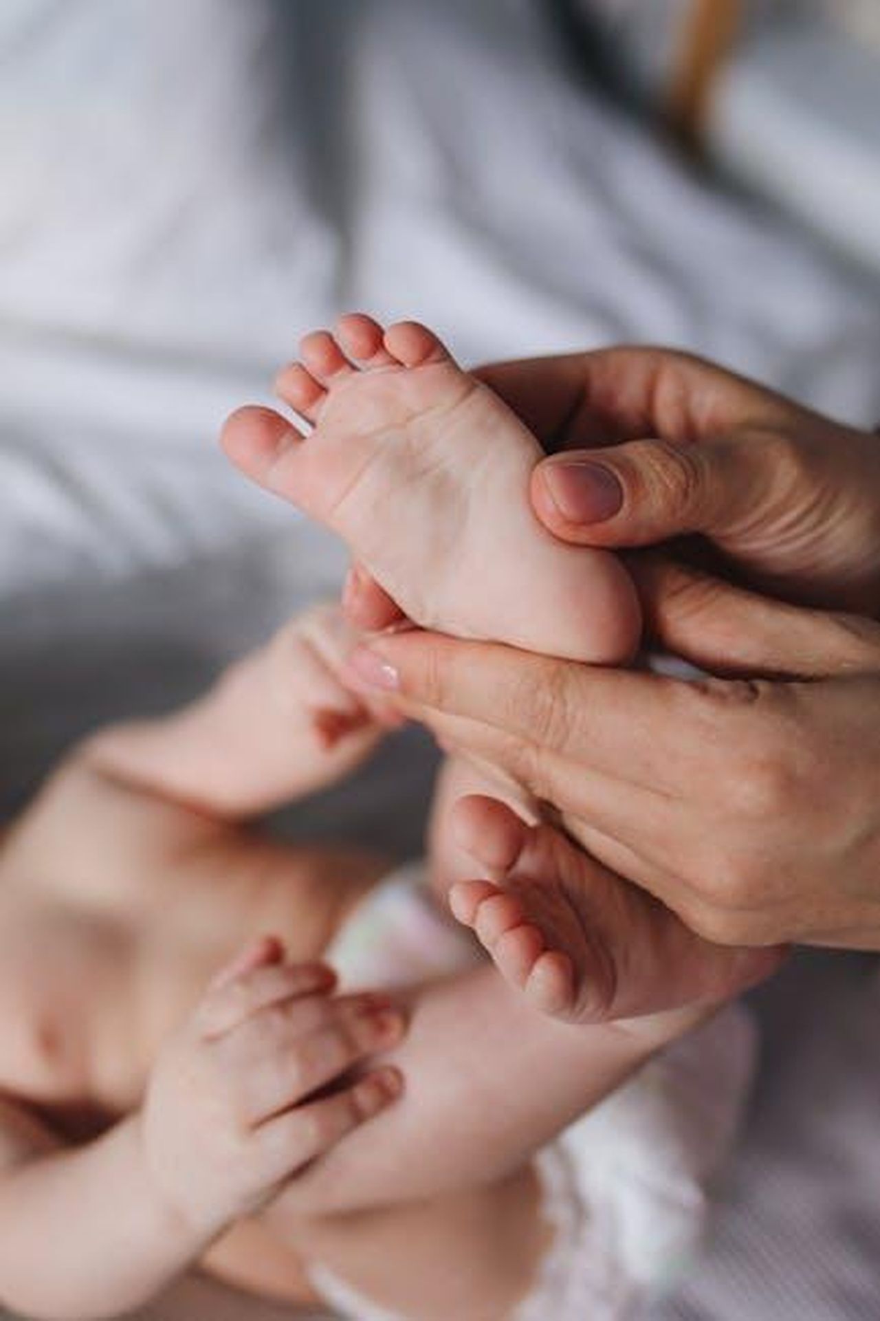 11_Vergine_lasciarsi_andare_lo6e0MDImh - Confidenze24 Source: Polina Tankilevitch - pexels - A close-up of a parent's hands gently massaging a baby's feet, showcasing tenderness and care.