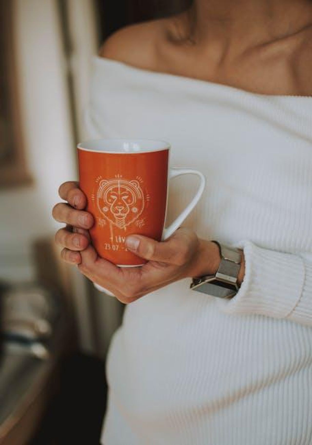 11_posto__Leone_V3zRF2Srnp - Confidenze24 Source: <a fref='https://www.pexels.com/@lilartsy' target='_new'>lil artsy</a> pexels - An adult woman holding a zodiac-themed mug indoors, wearing a white sweater.