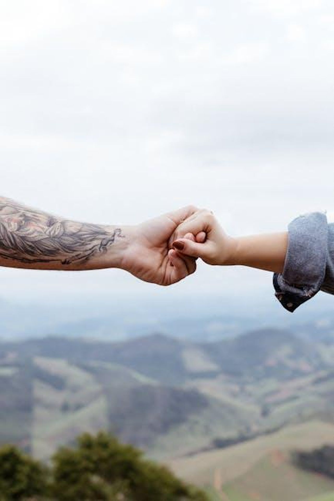 1_Bilancia_il_trionfo_dellarmonia_2GrCTfM1n8 - Confidenze24 Source: Jonathan Borba - pexels - Hands meeting against a mountainous backdrop symbolizing connection and togetherness.
