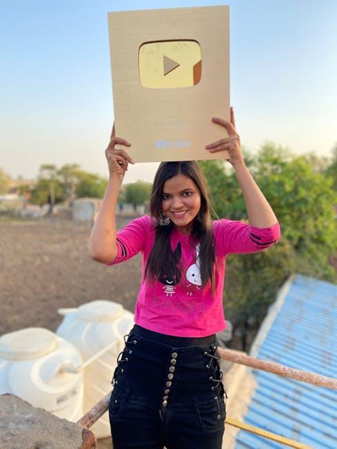 2017_Premio_al_Museum_of_the_Moving_Image_bGjNq9E3ze - Confidenze24 Source: Sonam Prajapati - pexels - Smiling woman holding a YouTube plaque outdoors in Umri, Madhya Pradesh.
