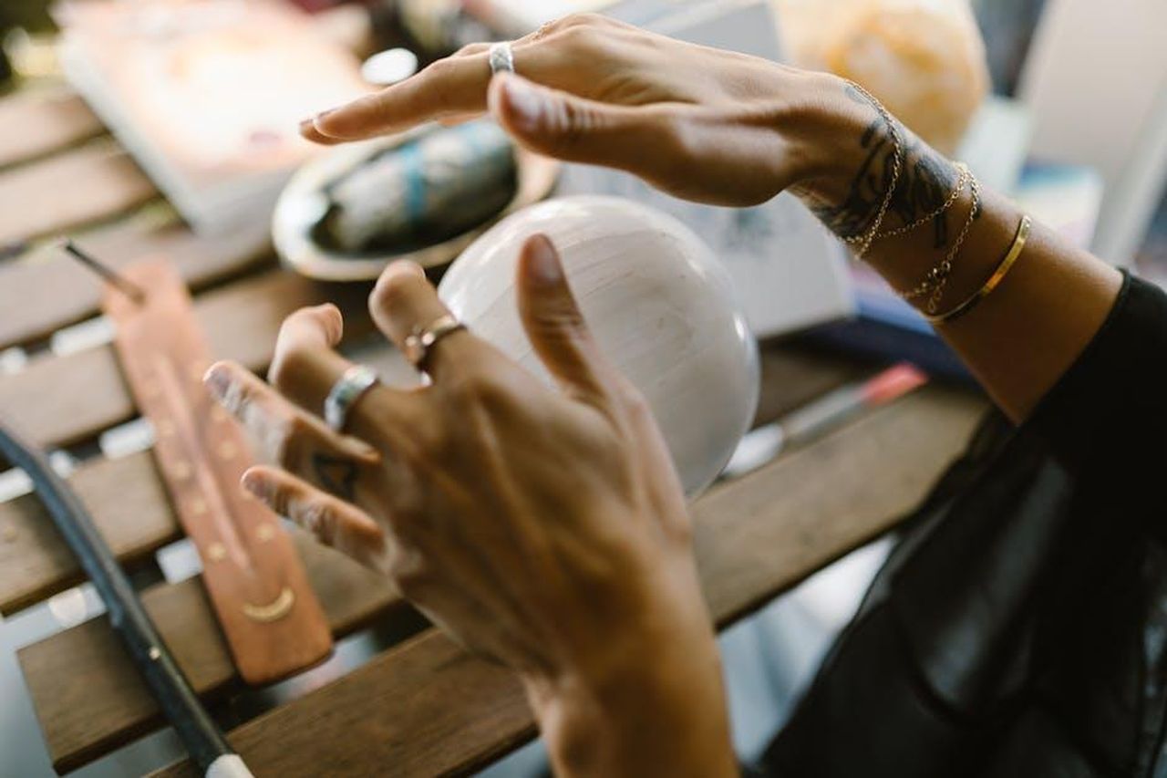 2_Acquario_oIiD3G3MPy - Confidenze24 Source: RDNE Stock project - pexels - A close-up of hands with jewelry interacting with a mystical crystal ball on a wooden table.