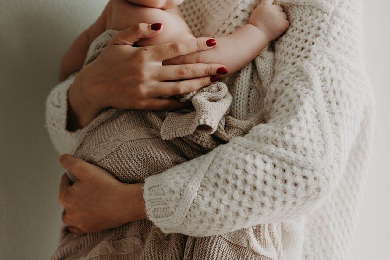 3_Capricorno_apertura_allamore_vvpDser53k - Confidenze24 Source: Kristina Paukshtite - pexels - Close-up of a mother holding her baby in warm knitwear, conveying love and togetherness.