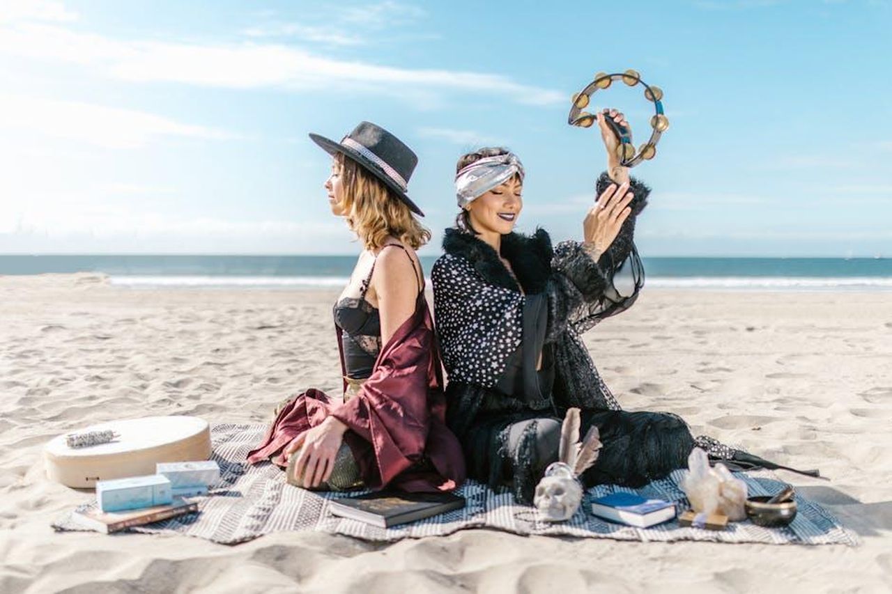 3_posto__Cancro_8yisHkVpuI - Confidenze24 Source: RDNE Stock project - pexels - Two women engage in a spiritual ritual on the beach with crystals and a tambourine, embodying bohemian vibes.