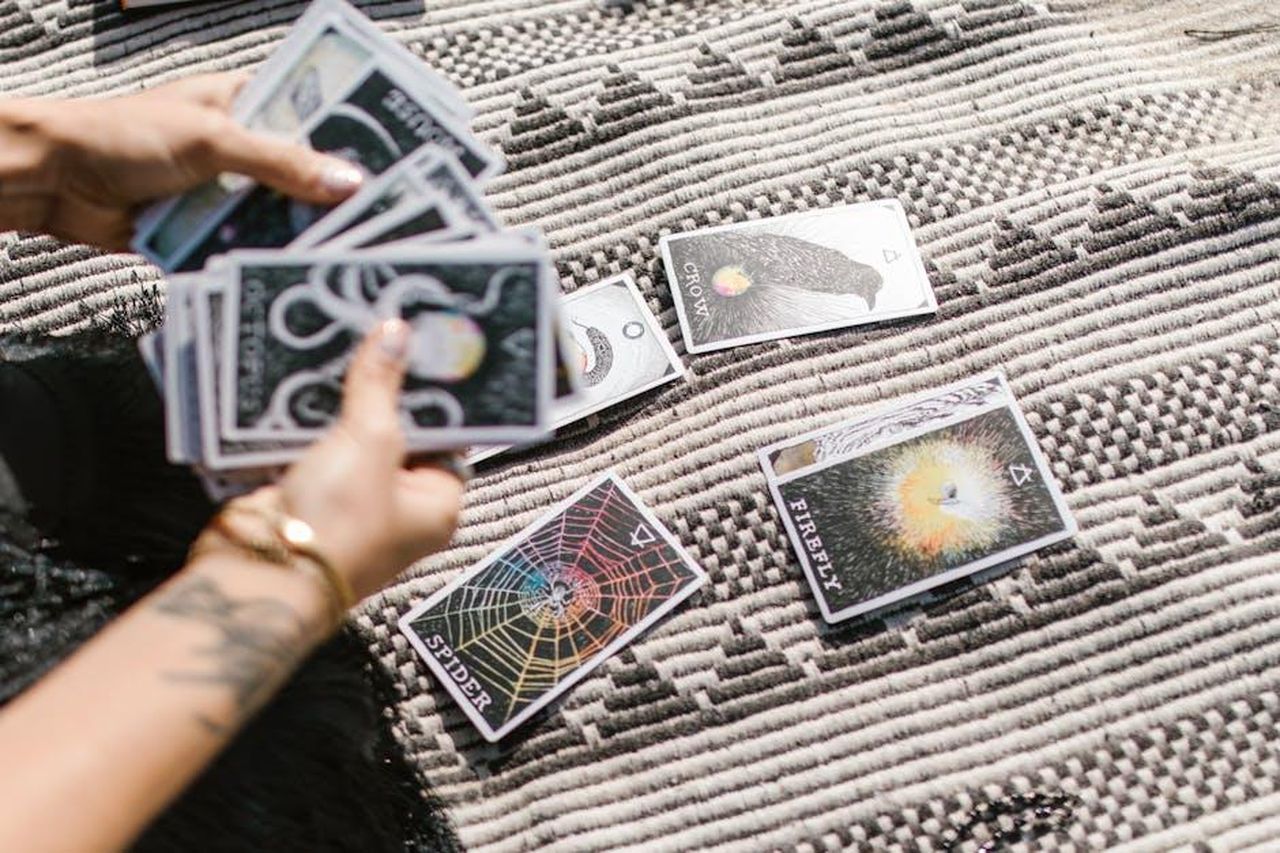4_Toro_sFFimpFYBA - Confidenze24 Source: RDNE Stock project - pexels - Hands dealing tarot cards for a reading on a stylish geometric rug.