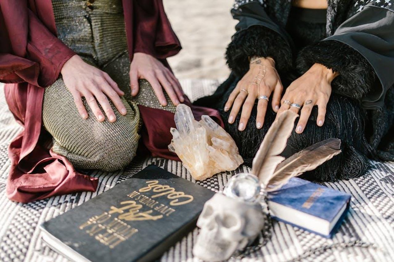 4_posto__Acquario_xCVhRtG8e7 - Confidenze24 Source: RDNE Stock project - pexels - A mystical scene with crystals, a skull, books, and hands in contemplative poses.