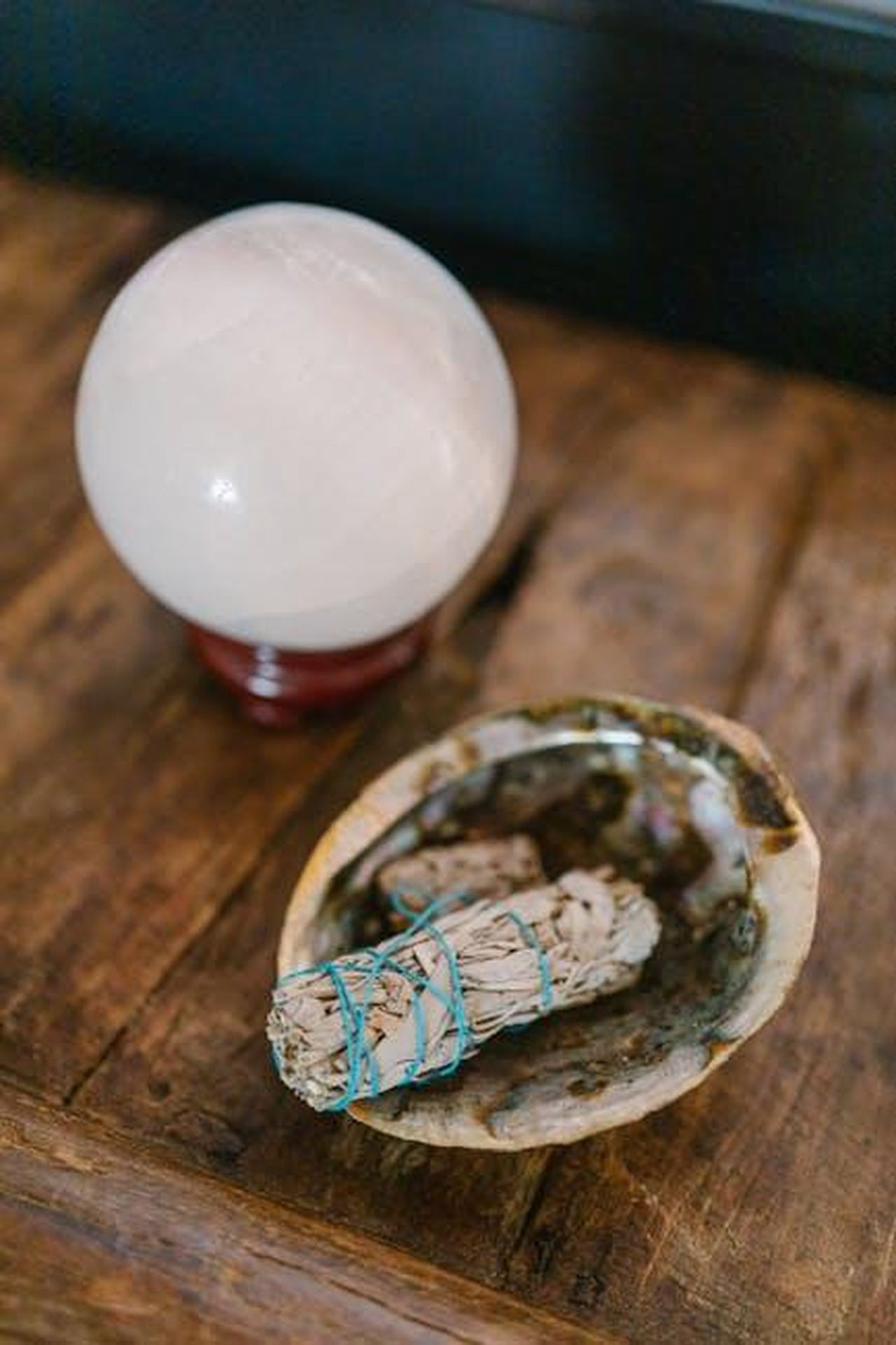 9_Ariete_flessibilit_nelle_sfide_professionali_5qWTQt09RI - Confidenze24 Source: RDNE Stock project - pexels - A crystal ball and sage bundle placed on a wooden table symbolize spirituality and cleansing.