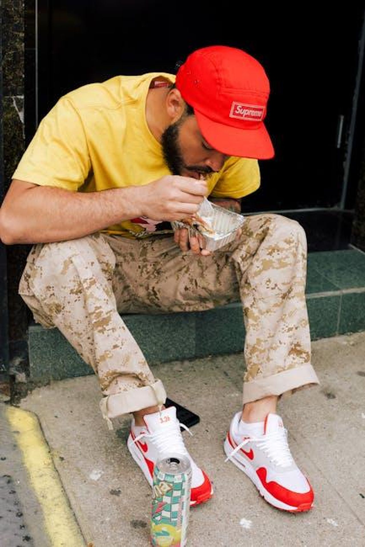 Adebayo_Sostiene_la_Nuova_Sneaker_di_AJa_Wilson_n0lFRf5y7X - Confidenze24 Source: Jonathon Burton - pexels - A fashionable man in a yellow shirt and red cap eats on the street, showcasing urban style.