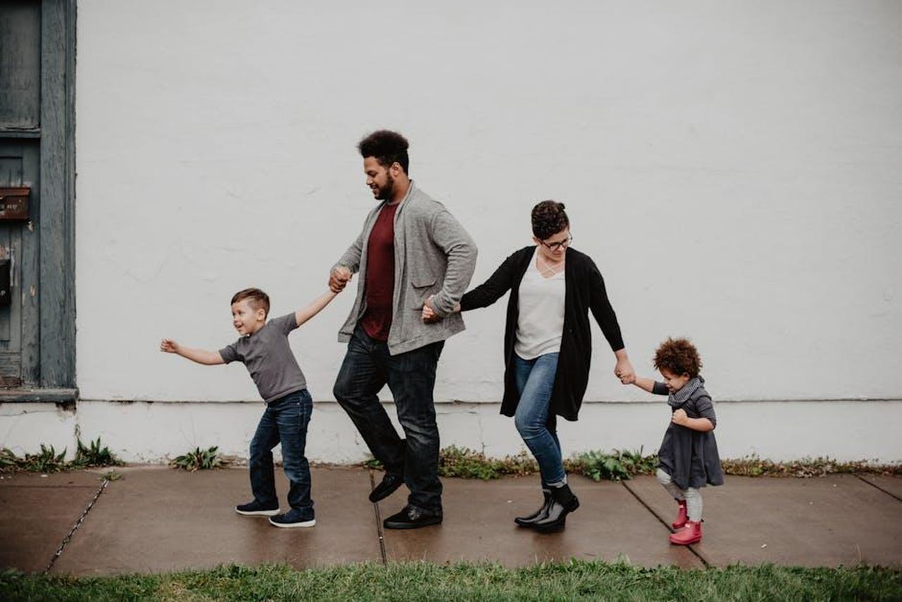 Affleck_si_concentra_sul_lavoro_e_sui_figli_661nmBZWSD - Confidenze24 Source: Emma Bauso - pexels - A joyful family walking together outdoors, holding hands in a playful and happy moment.