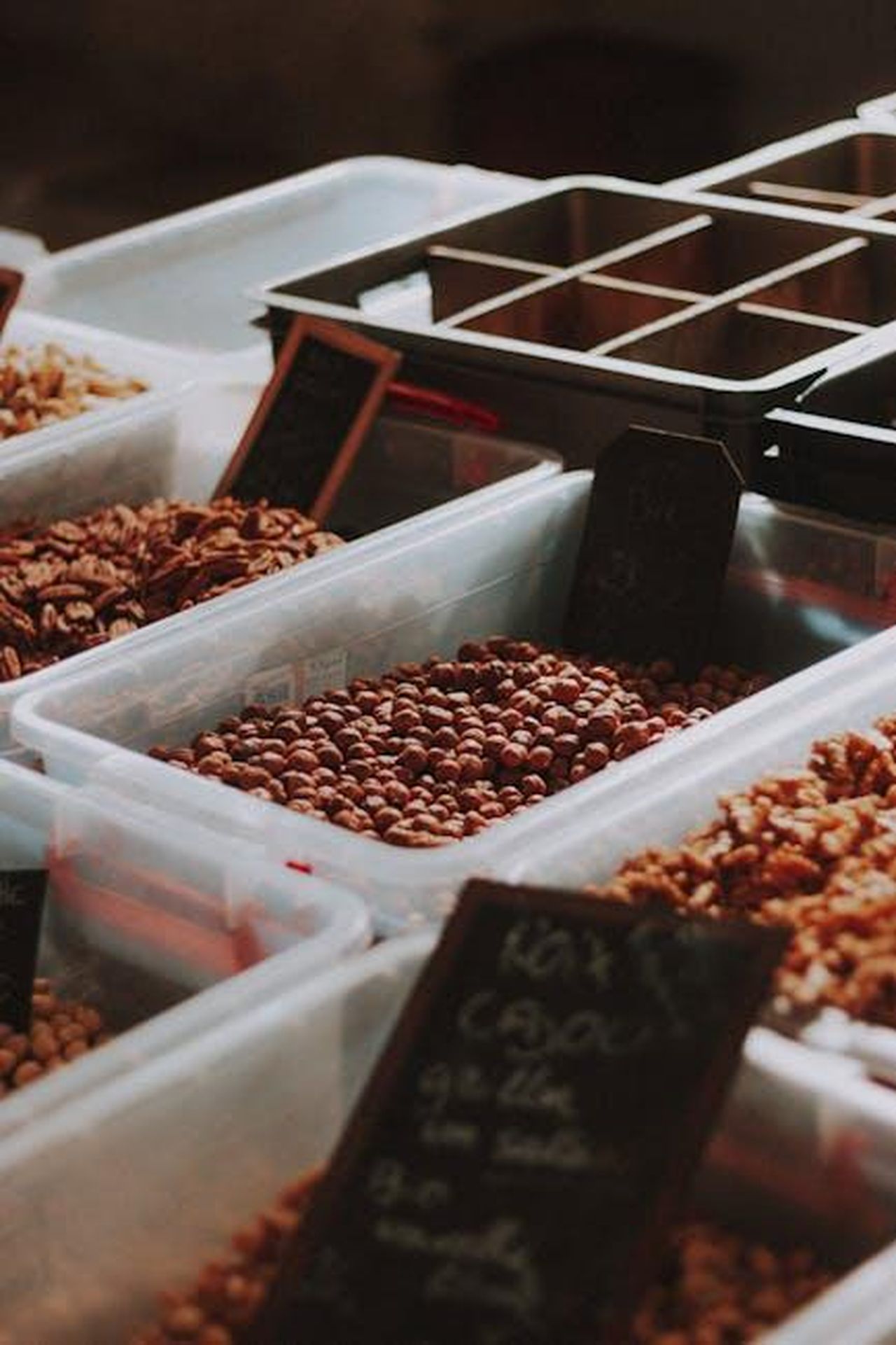 Altri_snack_popolari_di_Trader_Joes_ZWxwdB3KZ9 - Confidenze24 Source: Mathias Reding - pexels - Vertical shot of assorted nuts in plastic containers at a marketplace.