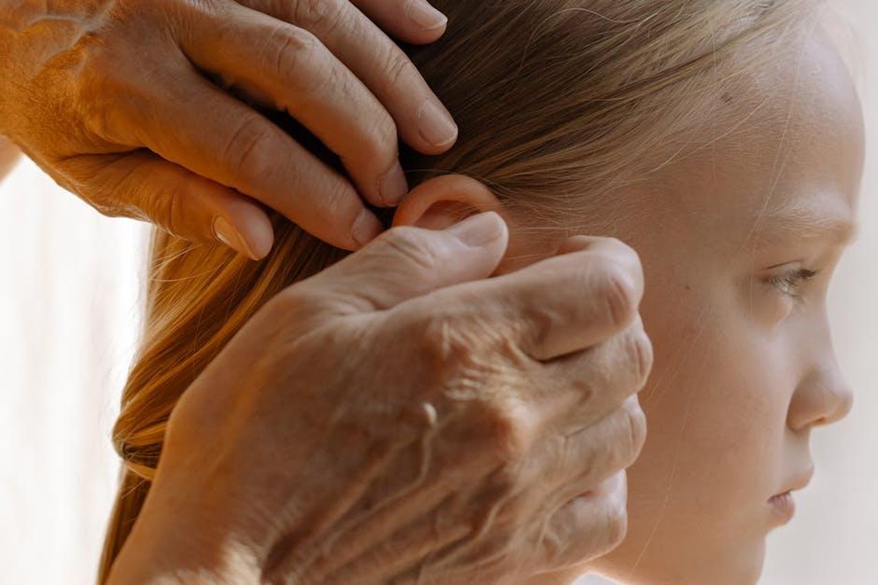 Aneddoti_sui_look_curati_per_artisti_ARUqzhko1s - Confidenze24 Source: cottonbro studio - pexels - A close-up of an elderly hand arranging a young girl's blonde hair indoors, highlighting multigenerational bond.