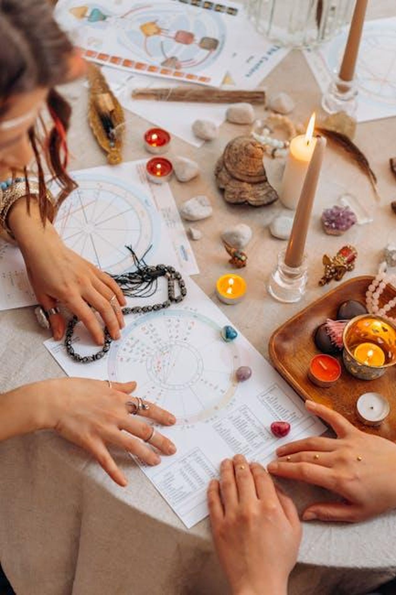 Ariete_piccole_crisi_da_superare_yLdcTaakWN - Confidenze24 Source: Mikhail Nilov - pexels - Hands arranging astrology charts with candles and crystals on a table for a spiritual ritual.