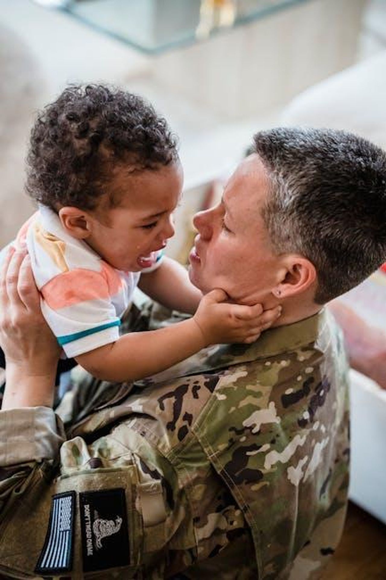 Autoironia_e_resilienza_FW0IeRs1RR - Confidenze24 Source: George Pak - pexels - A heartfelt reunion between a soldier in uniform and a crying child indoors.