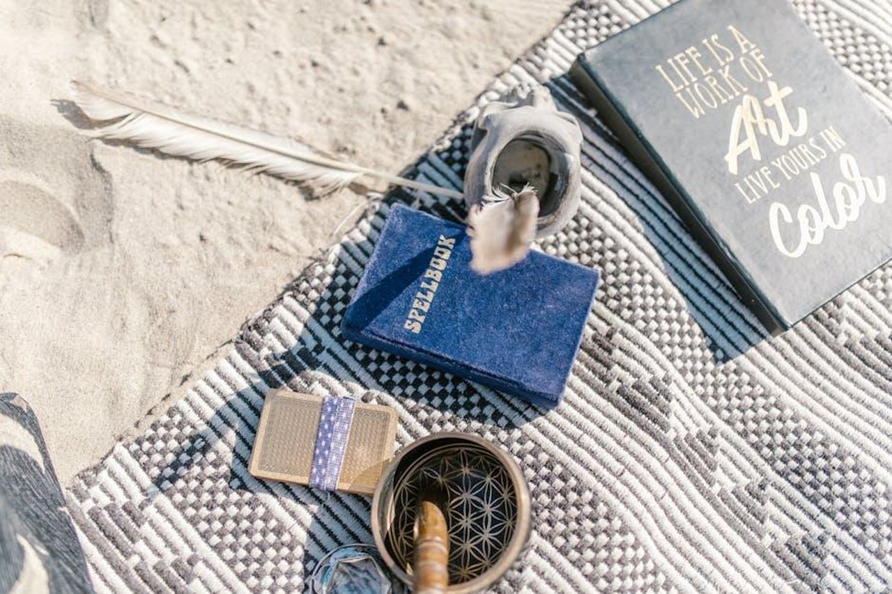 Bilancia_diplomazia_necessaria_JIJBfPU9DP - Confidenze24 Source: RDNE Stock project - pexels - A mystical setup on the beach with a spellbook, mandala, and inspirational quote book.