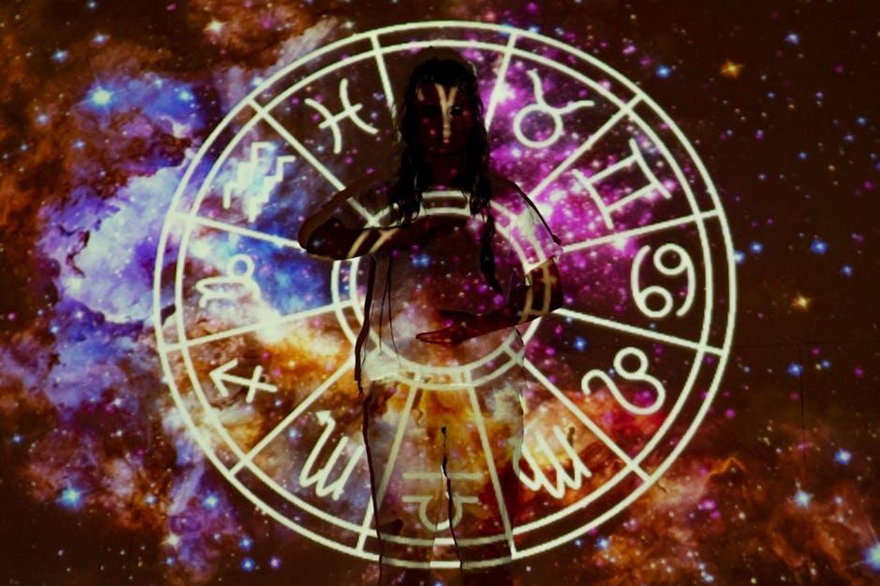 Cancro__Zhmuu9W9Ia - Confidenze24 Source: Mikhail Nilov - pexels - Woman standing with astrological symbols projected, evoking a mystical vibe.