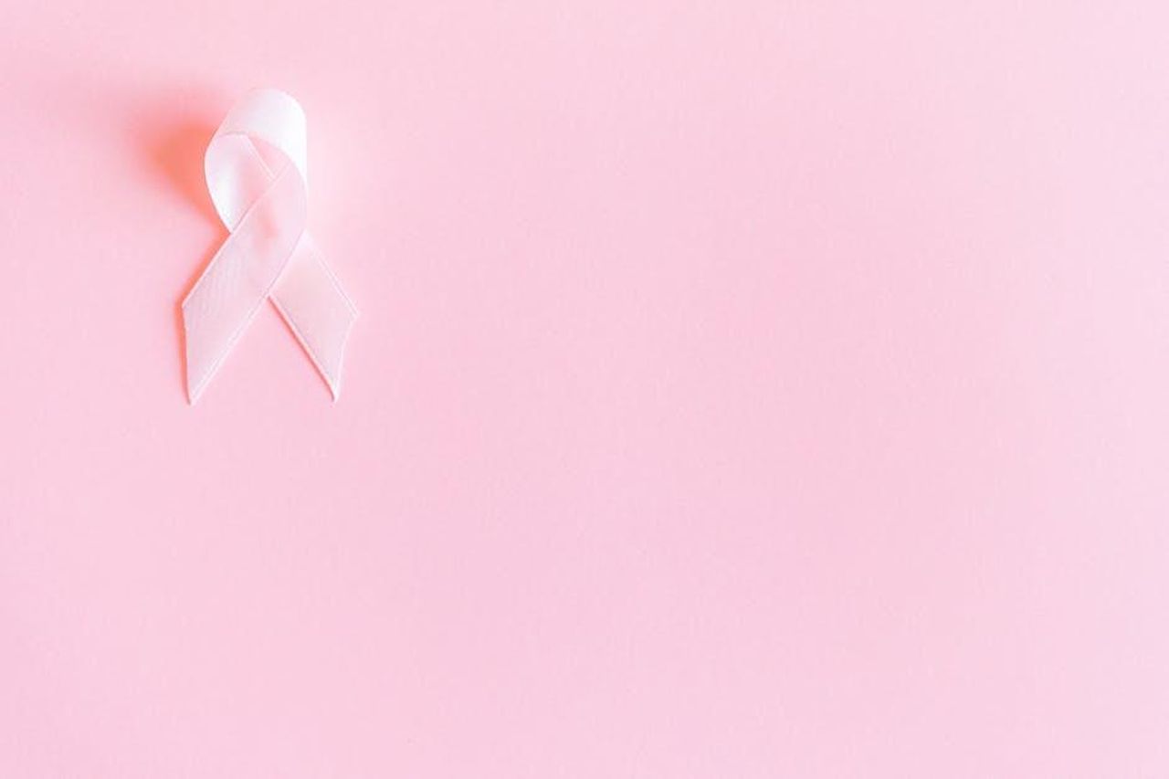 Cancro_giornata_positiva_in_amore_xHtijOAspZ - Confidenze24 Source: Anna Shvets - pexels - A pink ribbon on a soft pink background symbolizing breast cancer awareness and solidarity.