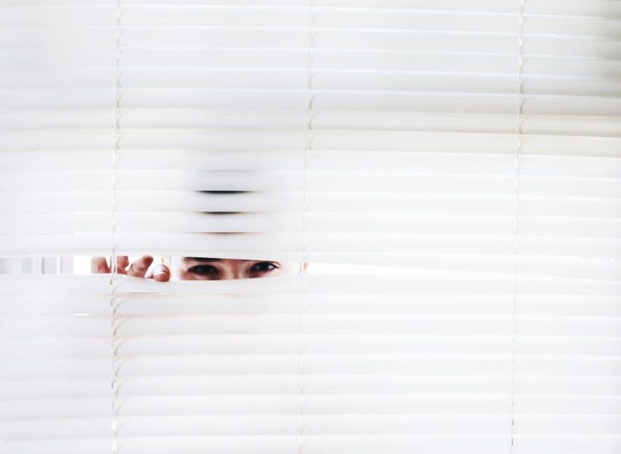 Candela_racconta_alcuni_segreti_di_Virtudes_Ng7EoJwOeV - Confidenze24 Source: Noelle Otto - pexels - A person peeks through white blinds, creating an intriguing sense of curiosity.