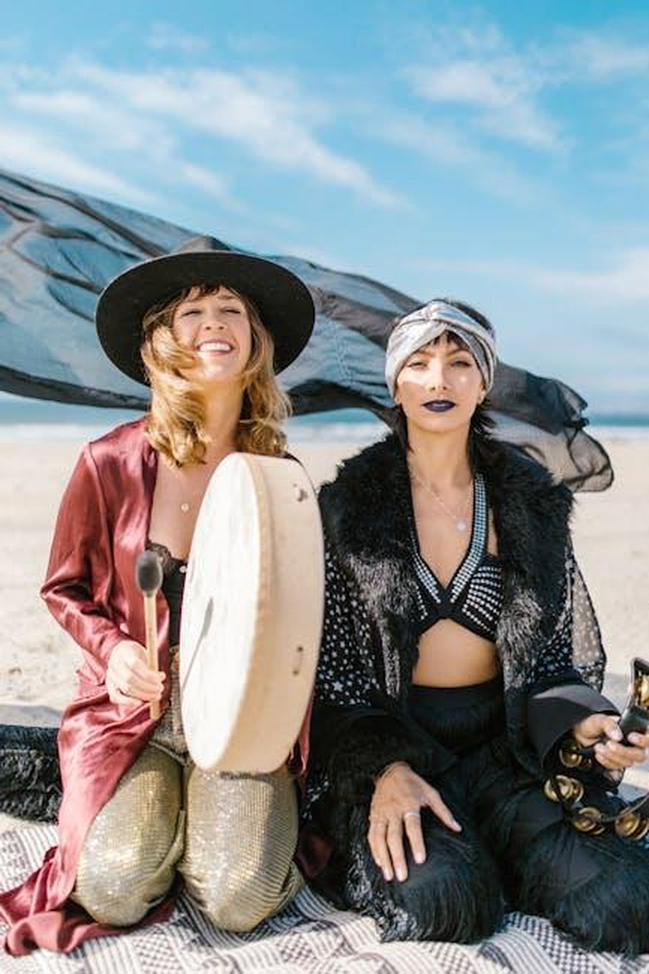 Capricorno_22_dicembre__19_gennaio_Xb40gLHERX - Confidenze24 Source: RDNE Stock project - pexels - Two women in bohemian attire with drums and tambourine on a sunny beach.