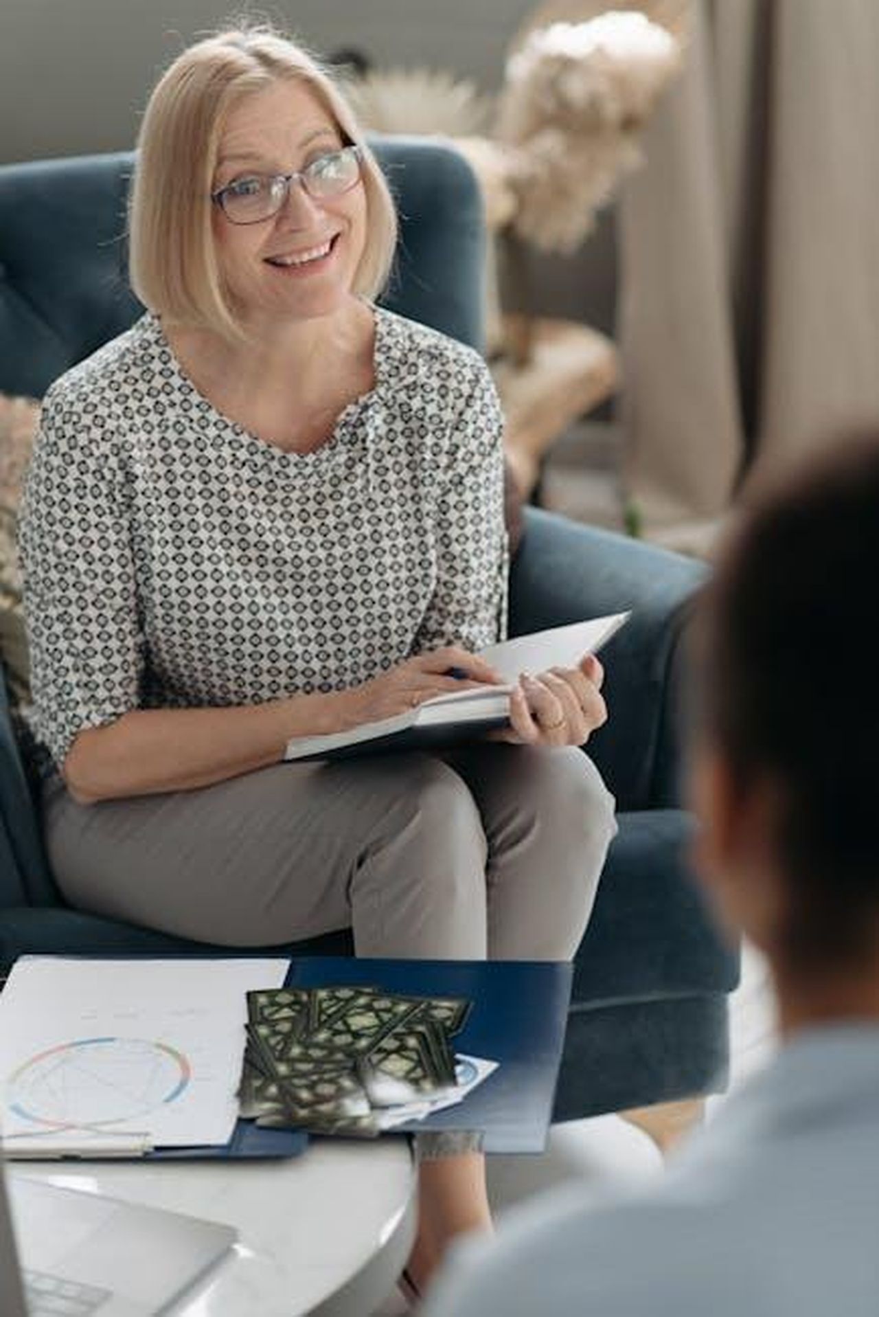 Capricorno__gNXCtKrWiv - Confidenze24 Source: Pavel Danilyuk - pexels - Smiling woman in a patterned blouse discussing horoscopes indoors.