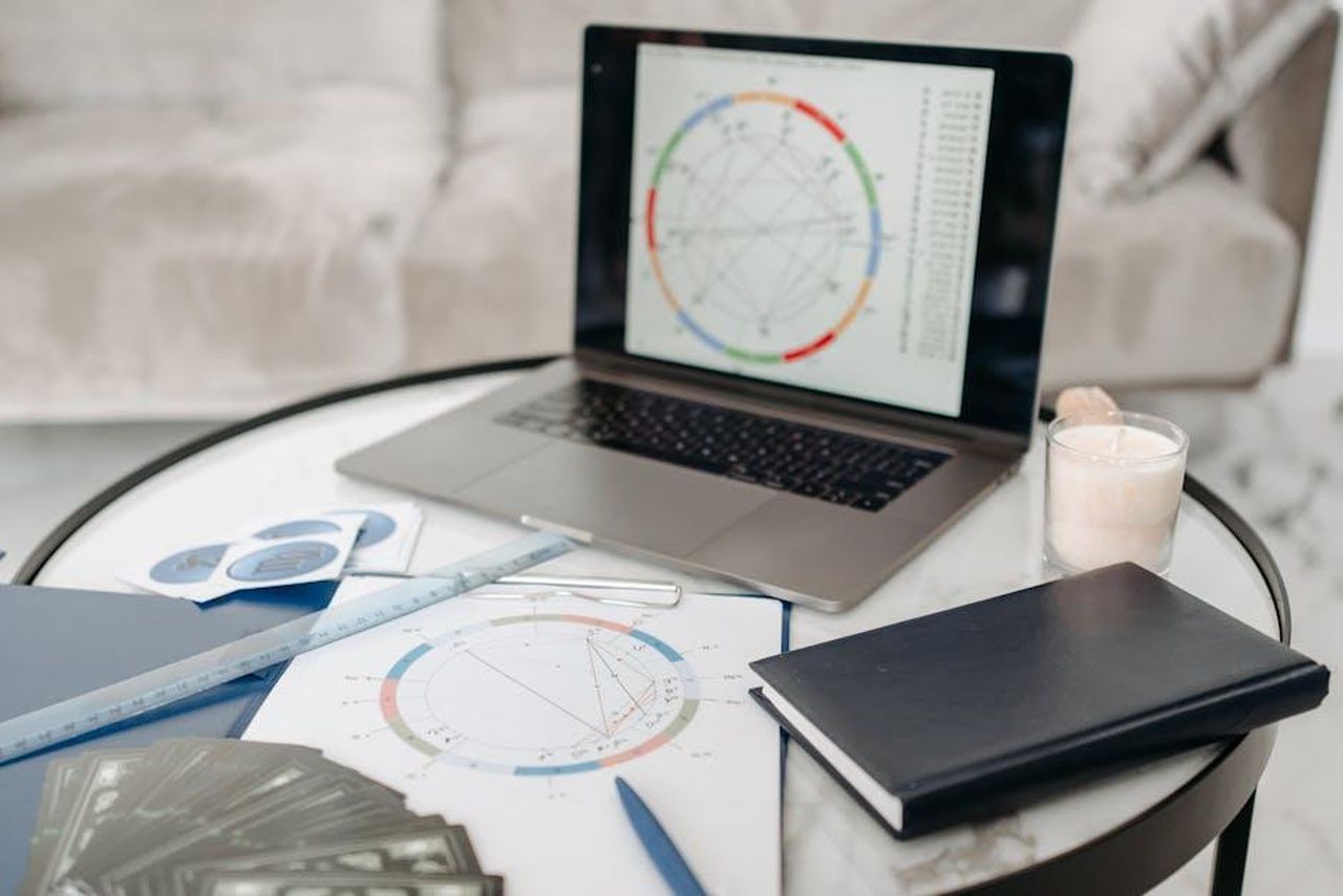 Capricorno_abitudinario_UajJ40gRau - Confidenze24 Source: Pavel Danilyuk - pexels - Astrology charts displayed on a laptop next to tarot cards and notebooks on a table.
