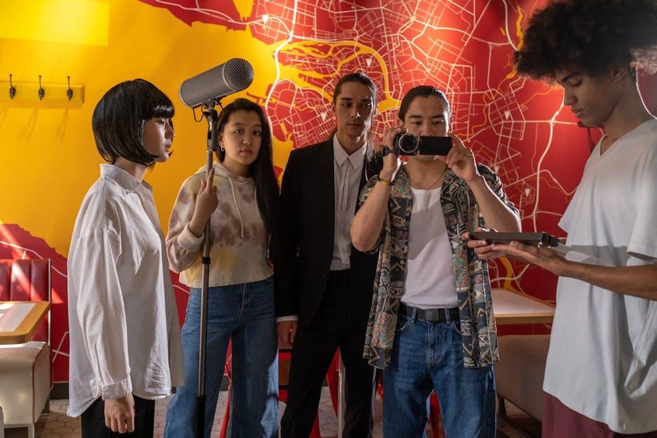 Cast_e_protagonisti_di_Una_babysitter_in_pericolo_P0X6HGYazz - Confidenze24 Source: Ron Lach - pexels - Film crew in action capturing an indoor movie scene with microphones and cameras, diverse cast.