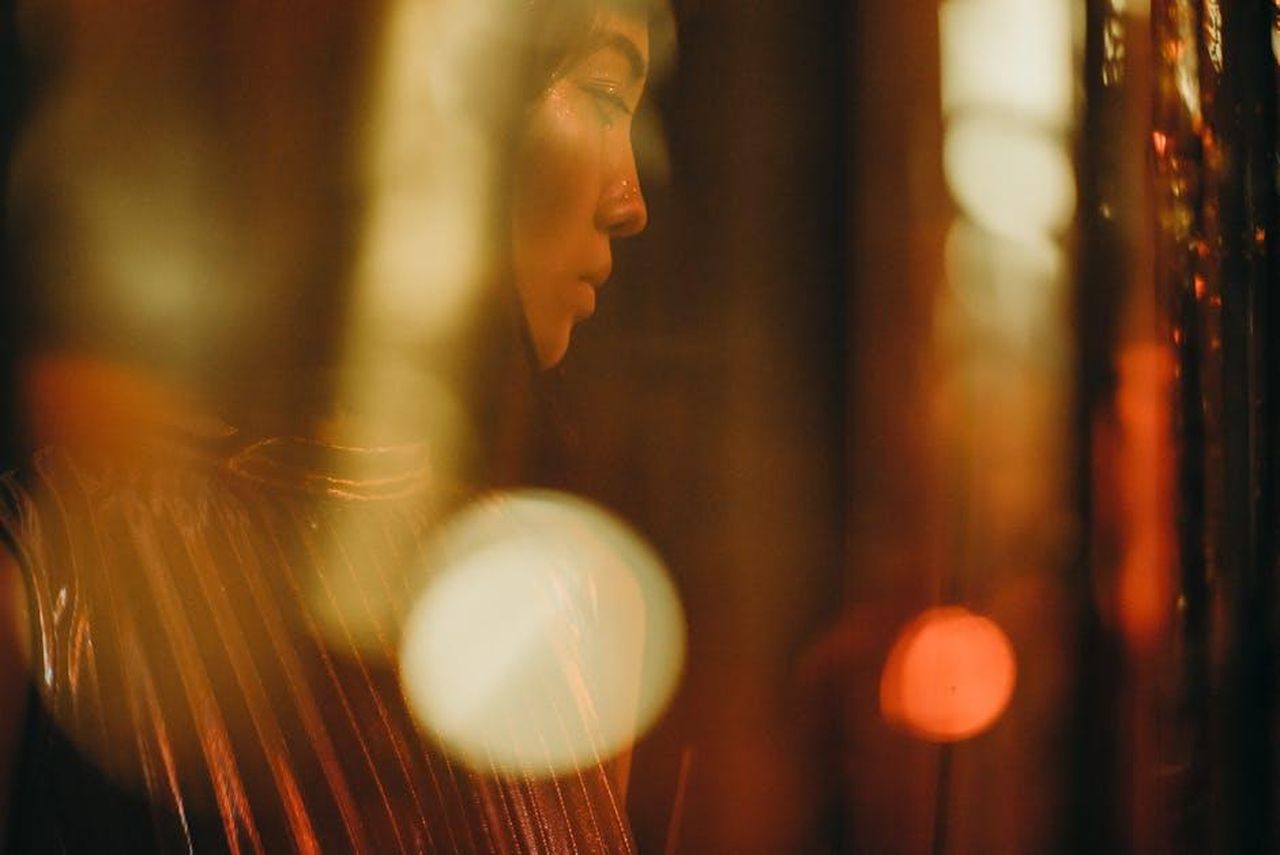 Celebrit_in_evidenza_Megan_Thee_Stallion_e_altri_z0SoQ9wXeY - Confidenze24 Source: cottonbro studio - pexels - Portrait of a woman highlighted by soft golden lighting at a festive, indoor event. Glamorous and mysterious.