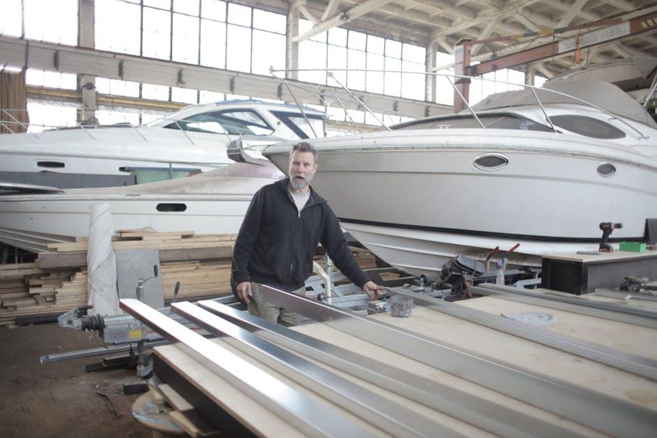 Chi__Edoardo_Ig9Sjydm9k - Confidenze24 Source: Andrea Piacquadio - pexels - Serious brutal male mechanic wearing casual clothes standing near metal details in spacious hangar with yachts