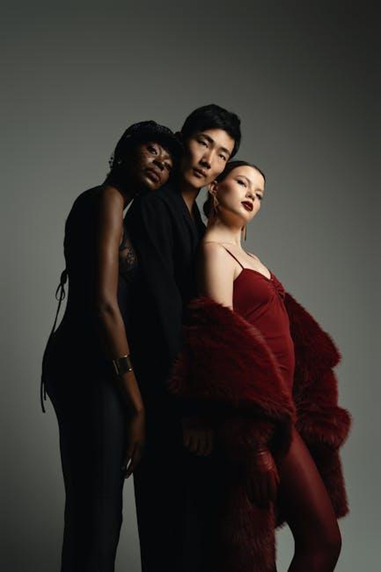 Collezione_Anthropologie_x_Good_American_pezzi_esclusivi_39CwqkOmSU - Confidenze24 Source: Jay Soundo - pexels - Three models pose elegantly in a studio, showcasing diverse fashion styles and moody lighting.