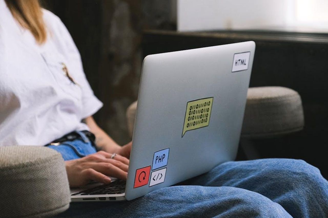 Come_cambia_la_programmazione_di_Tradimento_a_marzo_kudRoSDFiX - Confidenze24 Source: Anna Shvets - pexels - Person typing on a laptop with coding stickers, symbolizing remote work and freelancing.