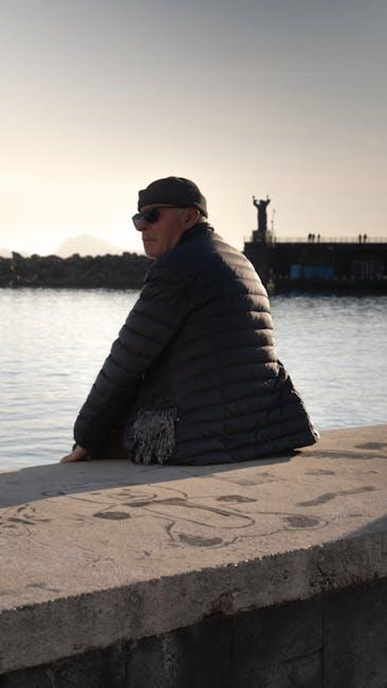 Come_giocherebbe_il_Napoli_con_il_possibile_ingaggio_di_Chemsdine_Talbi_Y0YKMzspfp - Confidenze24 Source: Ciro Palomba - pexels - Man in jacket sitting by the Napoli waterfront in warm light, enjoying the serene view.