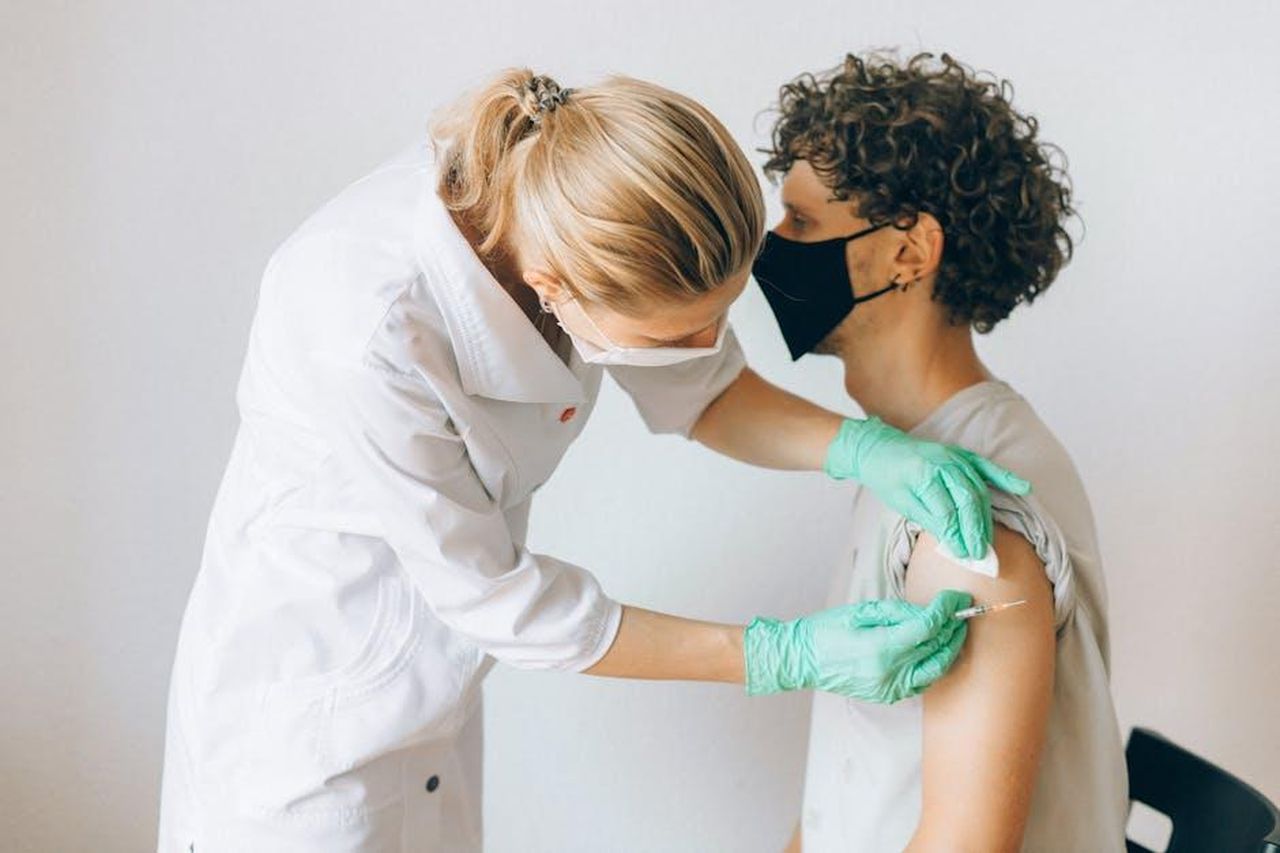 Complicazioni_per_gli_adulti_yIqXG7Jor7 - Confidenze24 Source: Nataliya Vaitkevich - pexels - A healthcare worker gives a vaccine shot to a patient wearing a mask, highlighting medical safety and health precautions.