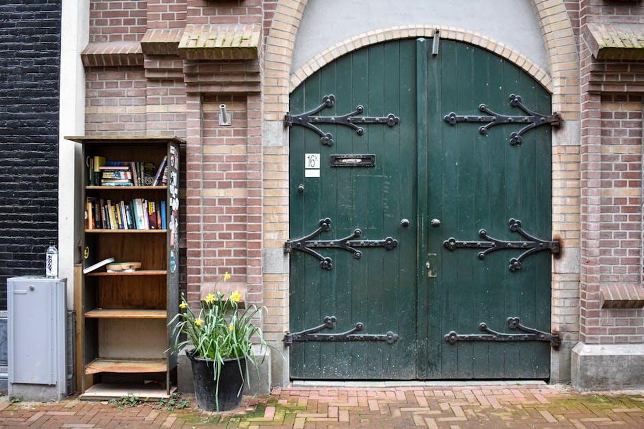 Condivisione_della_malattia_con_il_pubblico_2H138E8VTh - Confidenze24 Source: Maria-Theodora Andrikopoulou - pexels - A street library with books next to a green arched door in Amsterdam.