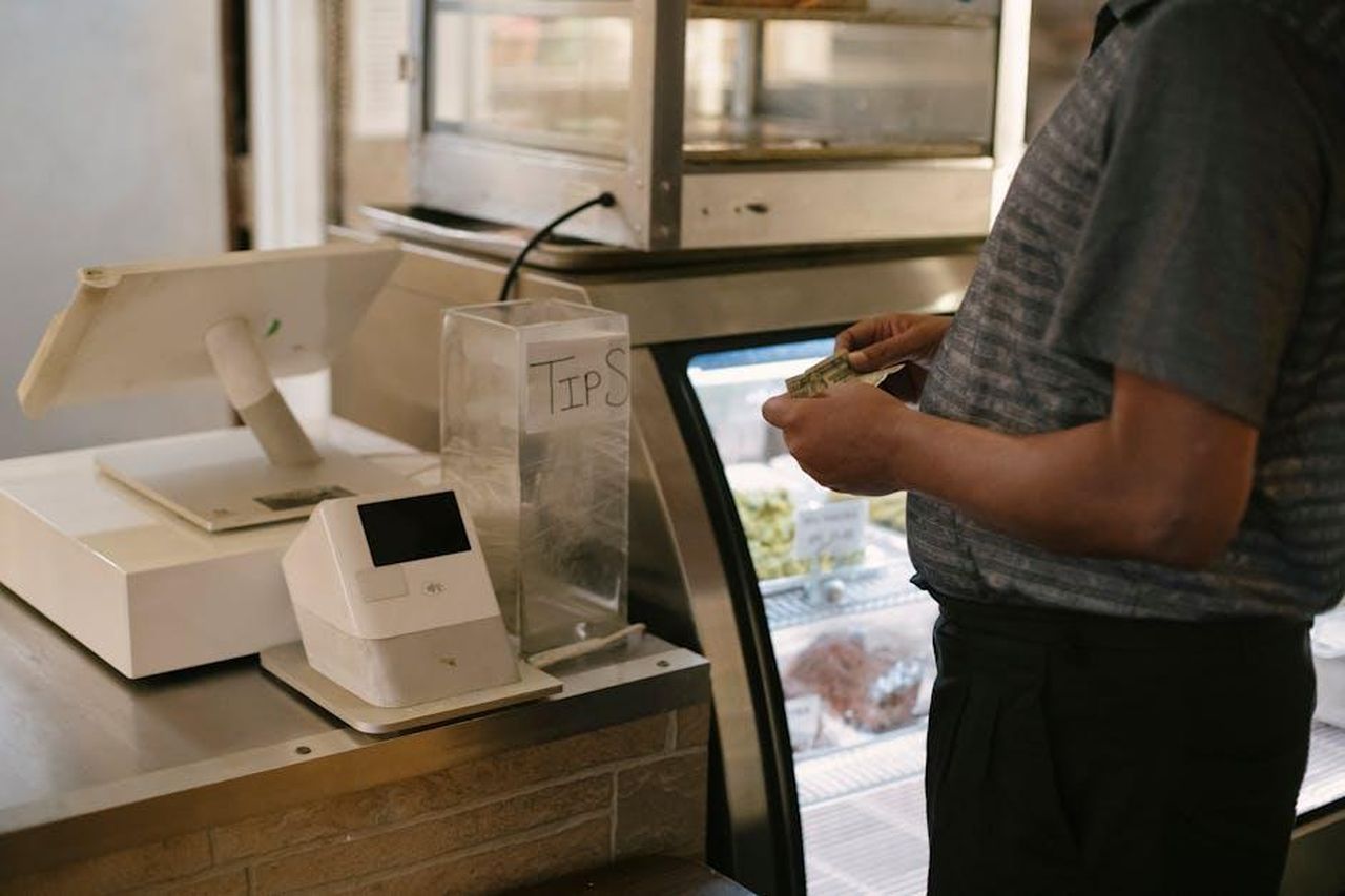 Consigli_per_lacquisto_della_collezione_6YQybUMpRZ - Confidenze24 Source: Tim Samuel - pexels - Unrecognizable male in casual clothes standing with money near cash register in grocery store while making purchase near glass showcase