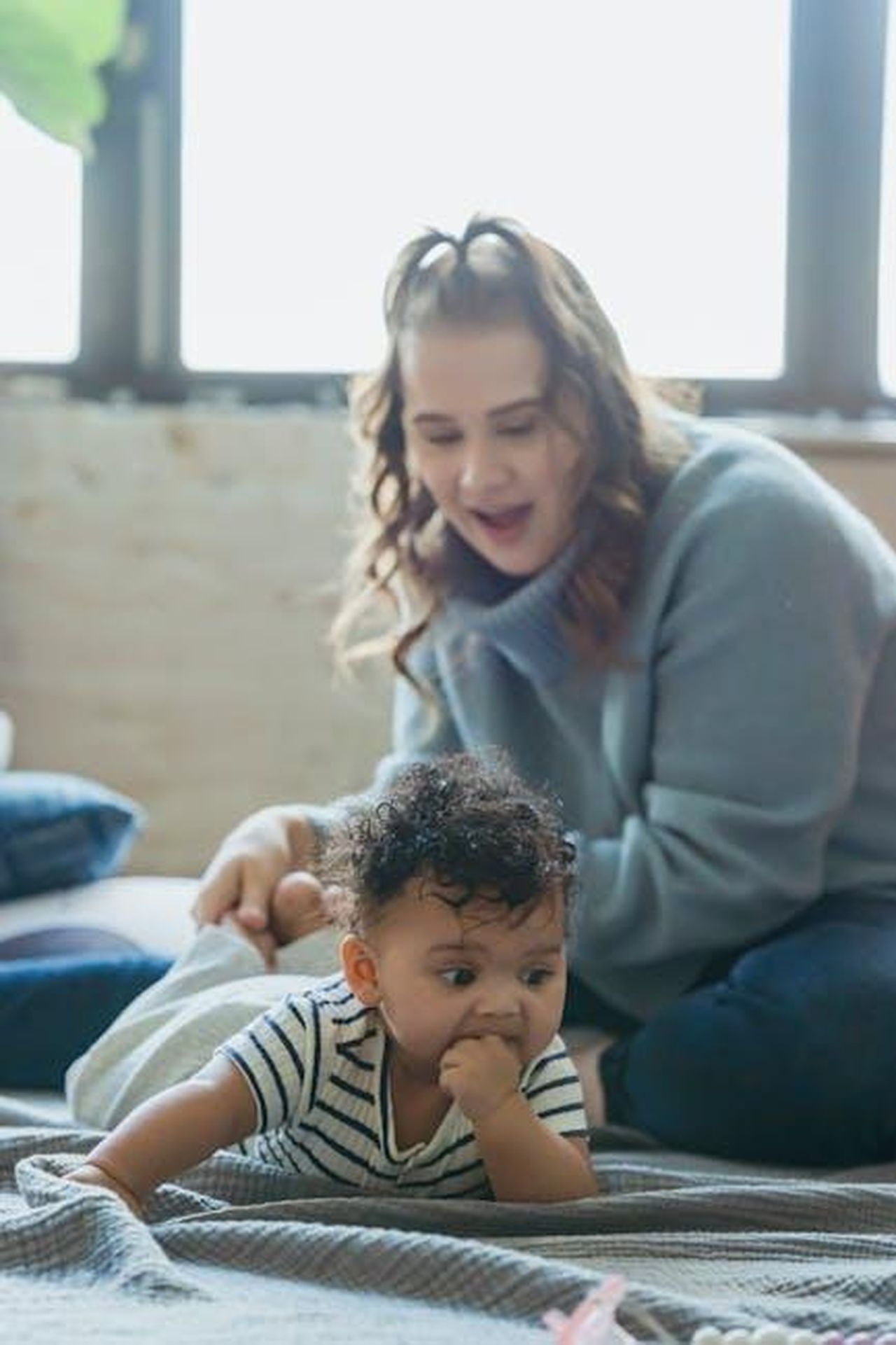 Curiosit_e_notizie_in_risalto_eFYcNwEIcp - Confidenze24 Source: Keira Burton - pexels - Woman playing with ethnic toddler on blanket with pillows on floor in light apartment