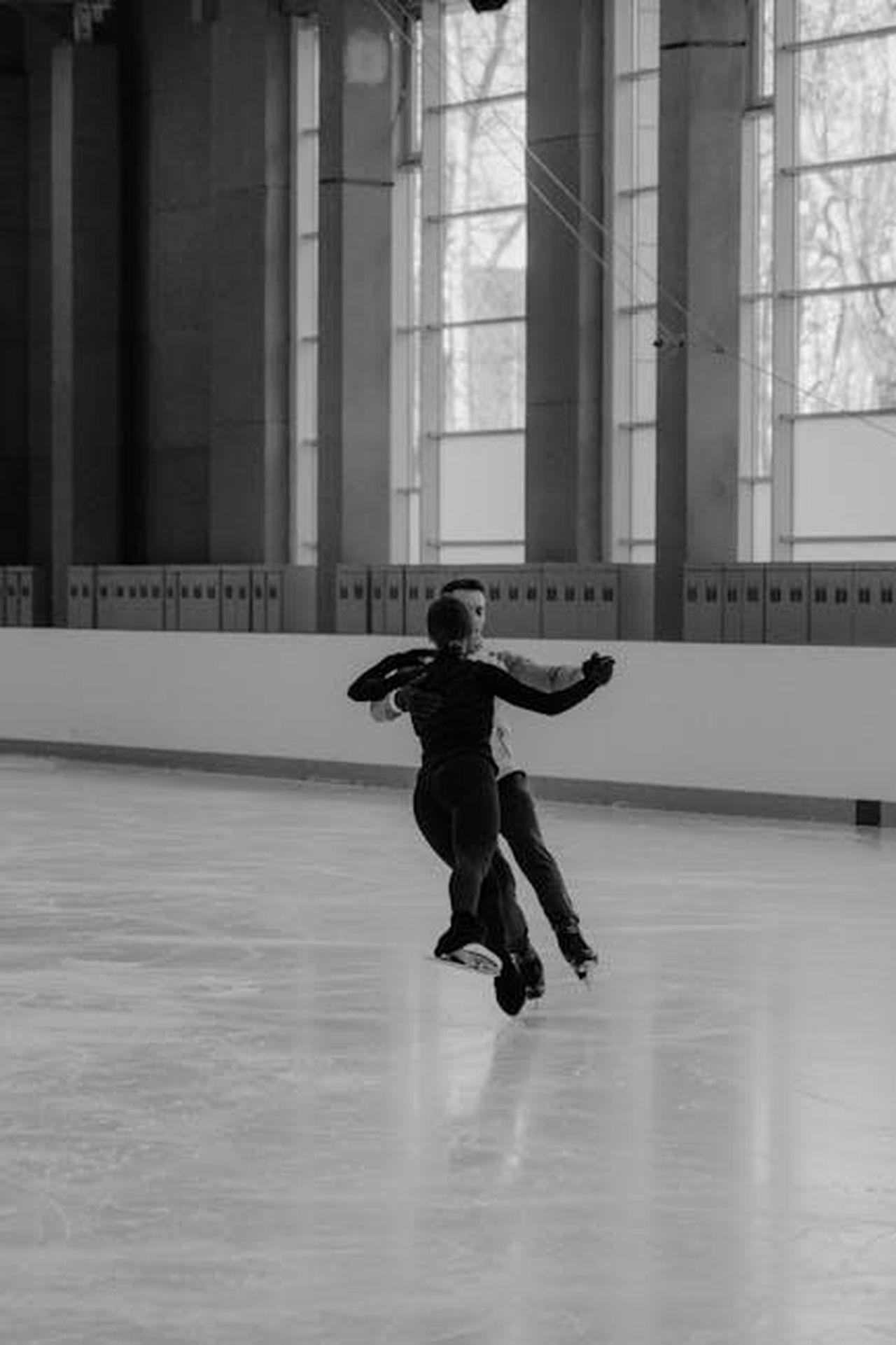 Dancing_On_Ice_semifinale__chi__rimasto_lf8hUMG01s - Confidenze24 Source: Tima Miroshnichenko - pexels - Elegant black and white capture of a figure skating pair gracefully performing on an indoor ice rink.