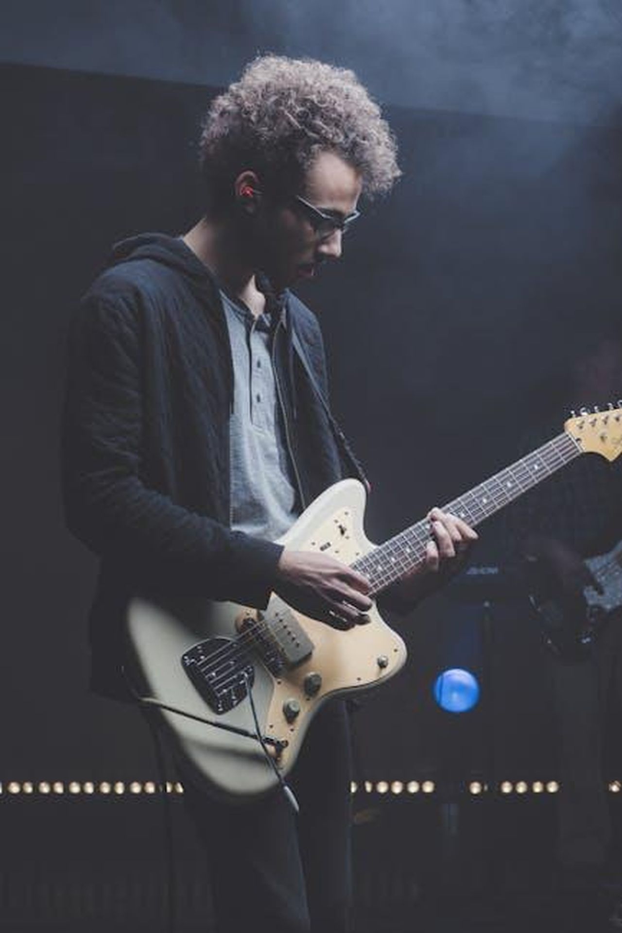 Dettagli_sulla_condanna_e_il_caso_di_Pop_Smoke_JtTV9Dm20G - Confidenze24 Source: Ryan Holloway - pexels - A talented guitarist performing in a moody live concert setting with vibrant lighting.