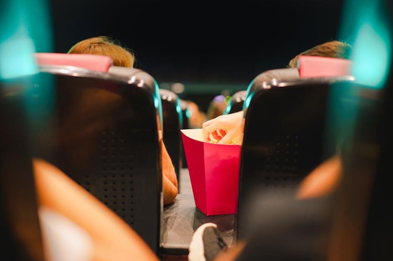 Dinamiche_amorose_e_tensioni_cu5LSn1B9H - Confidenze24 Source: Jakub Zerdzicki - pexels - Group enjoying popcorn in a contemporary cinema setting, enhancing the movie experience.