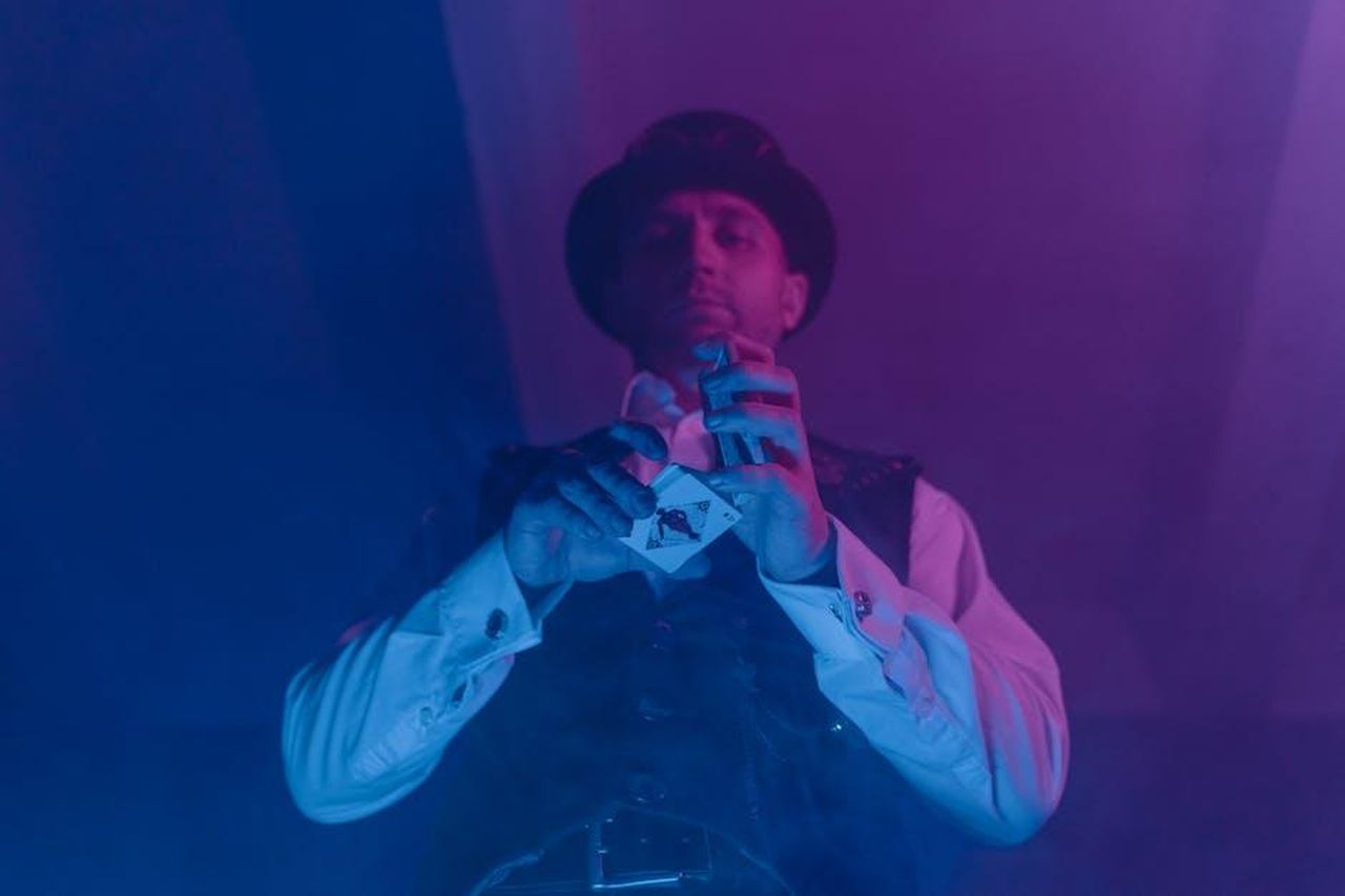 Divertimento_con_Lee_Mack_e_atmosfera_disco_sul_set_m1RldGEx5Z - Confidenze24 Source: Tima Miroshnichenko - pexels - A magician showcases a captivating card trick under colorful lighting, creating an aura of mystery.
