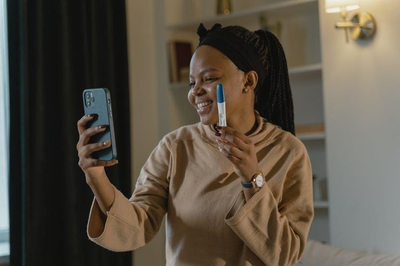 Elmas_informer_la_famiglia_di_Tarik_6lz1KpqIx6 - Confidenze24 Source: Tima Miroshnichenko - pexels - Joyful woman holding a positive pregnancy test while video calling indoors.