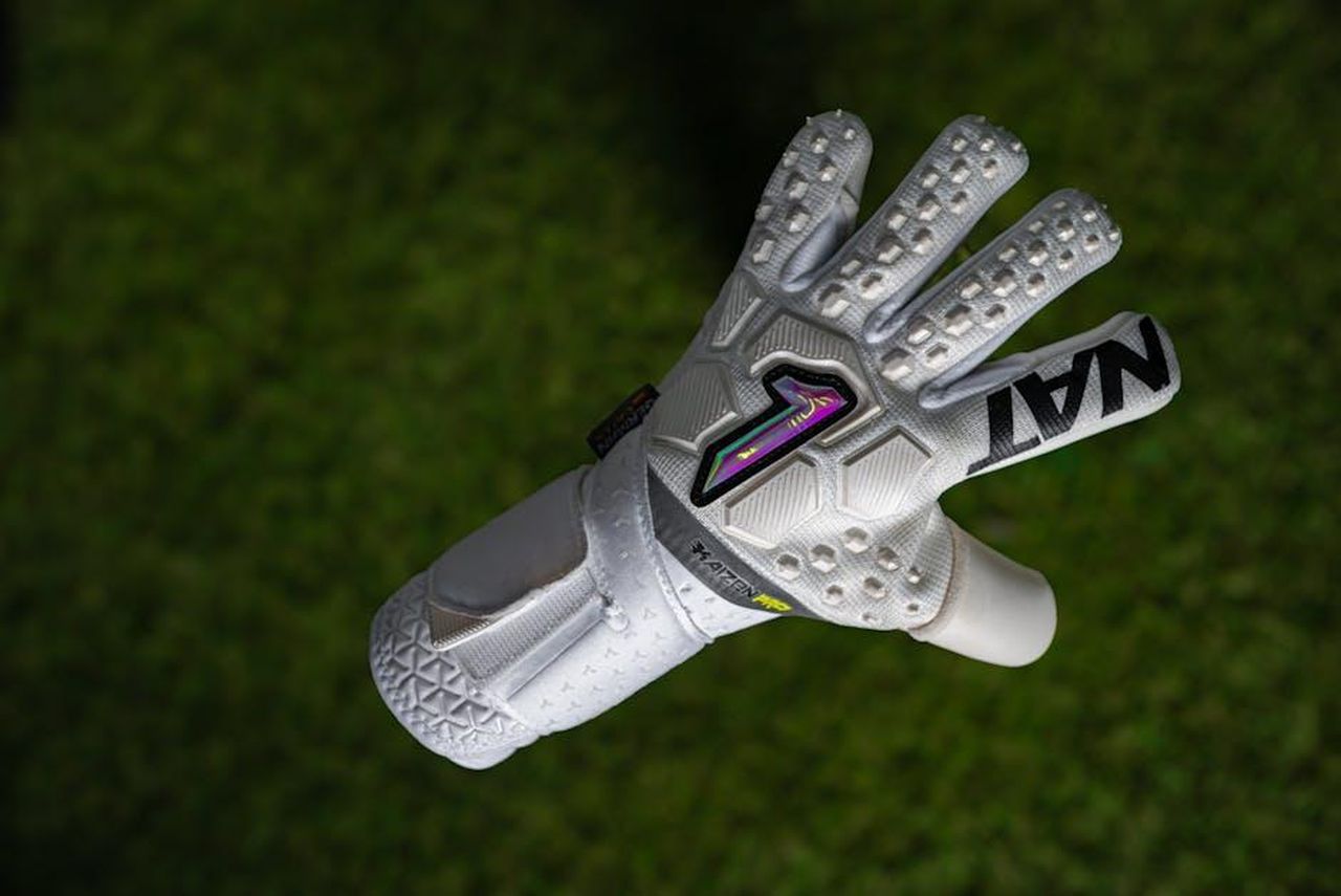 Emilio_Longo_riparte_dalla_gara_contro_il_Monopoli_b8aJX1ygFY - Confidenze24 Source: Jonatan Gomez - pexels - Close-up of a white goalkeeper glove on lush green grass, suitable for sports-focused visuals.