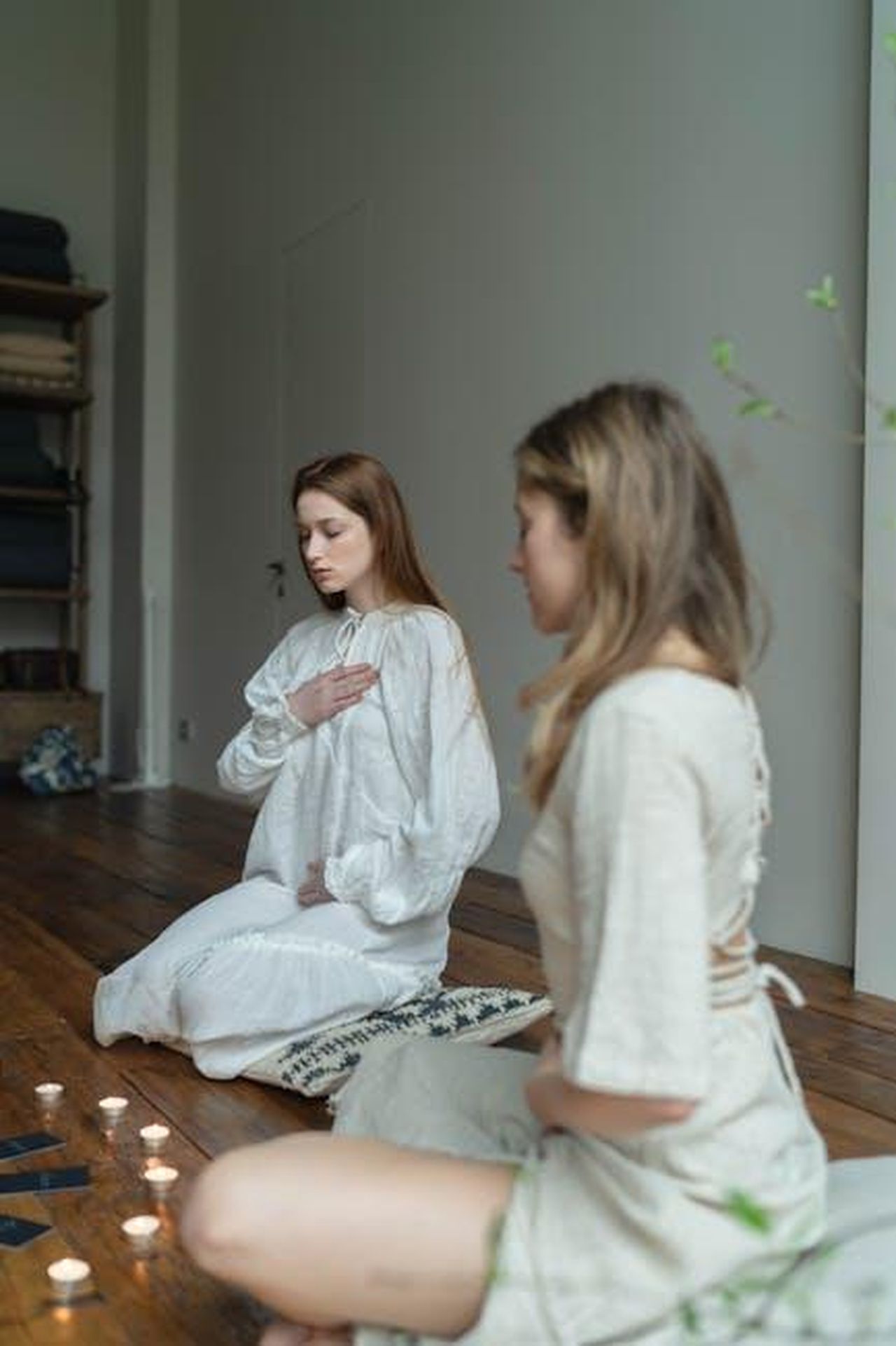 Erbe_da_utilizzare_durante_la_stagione_delle_eclissi_Erw8M1upau - Confidenze24 Source: Anastasia Shuraeva - pexels - Two women meditating in a calm indoor setting surrounded by candles.