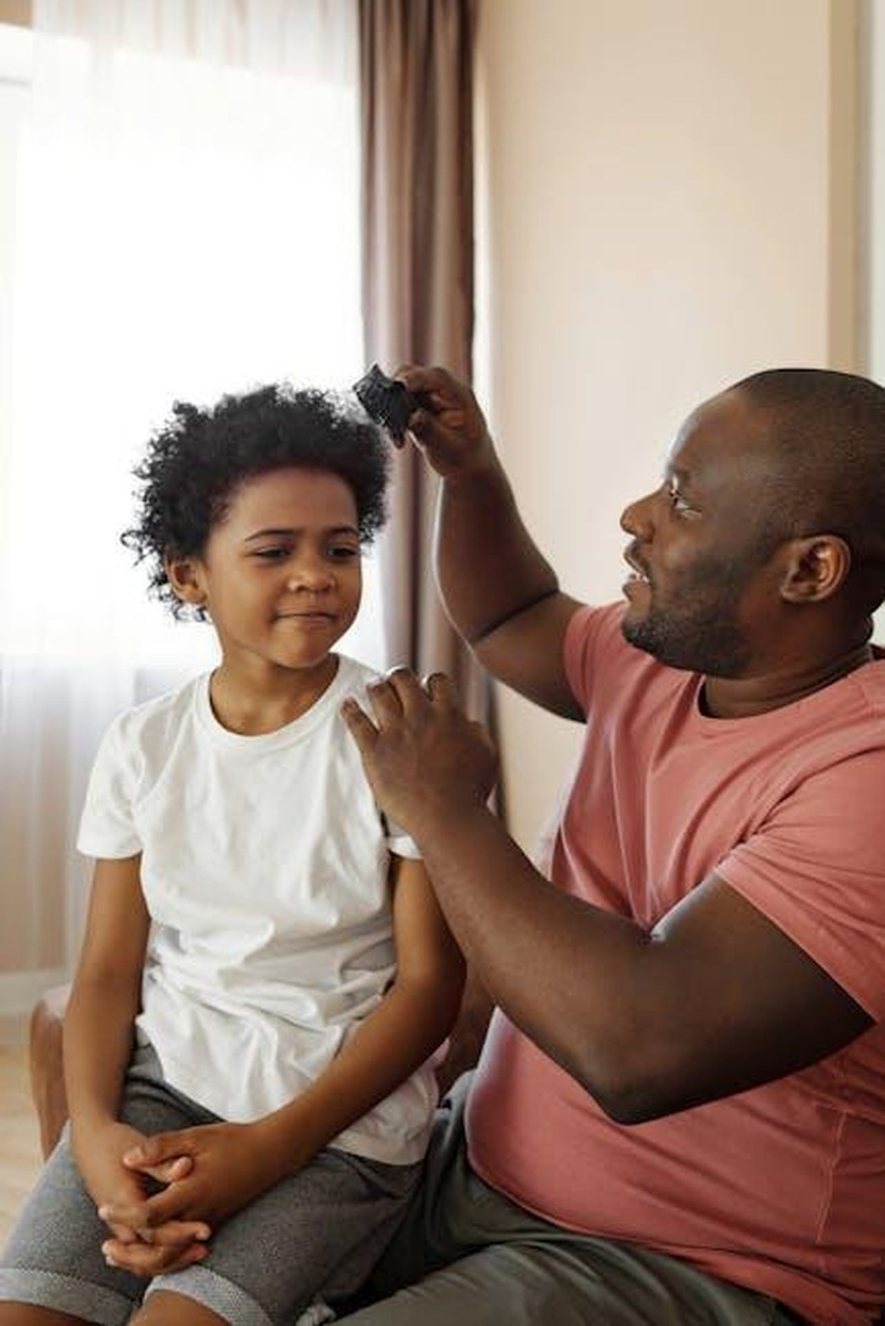 Federico_parla_del_figlio_e_dellamore_per_la_ex_compagna_Lr4s5ATnR8 - Confidenze24 Source: August de Richelieu - pexels - A father brushes his son's curly hair, showcasing love and parenthood indoors.