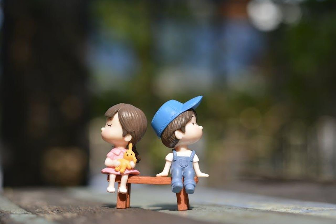 Finn_e_Steffy_un_amore_in_pericolo_VDNEWAxay6 - Confidenze24 Source: KawaiiArt1980 - pexels - Adorable figurines of a boy and girl sit on a bench, bathed in summer sunlight.