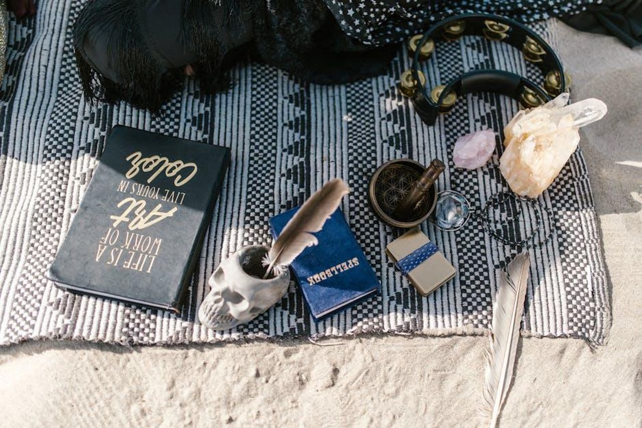 Gemelli__TbL3goedJv - Confidenze24 Source: RDNE Stock project - pexels - Flat lay of spiritual tools with crystals, skull cup, and feathers on a blanket outdoors.