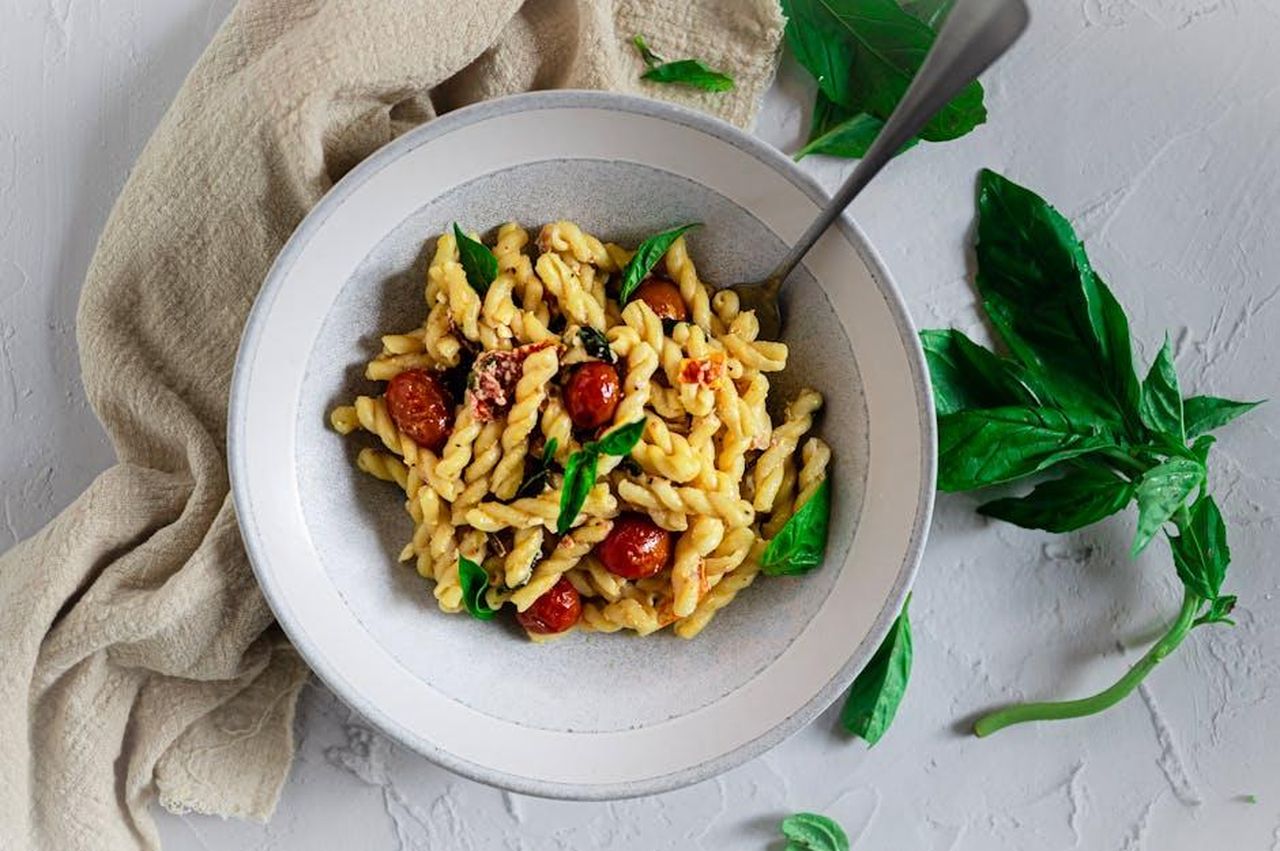Gemelli_giornata_luminosa_kaN8vGy7dZ - Confidenze24 Source: eat kubba - pexels - Top view of gemelli pasta with cherry tomatoes and basil, ideal for Italian cuisine enthusiasts.