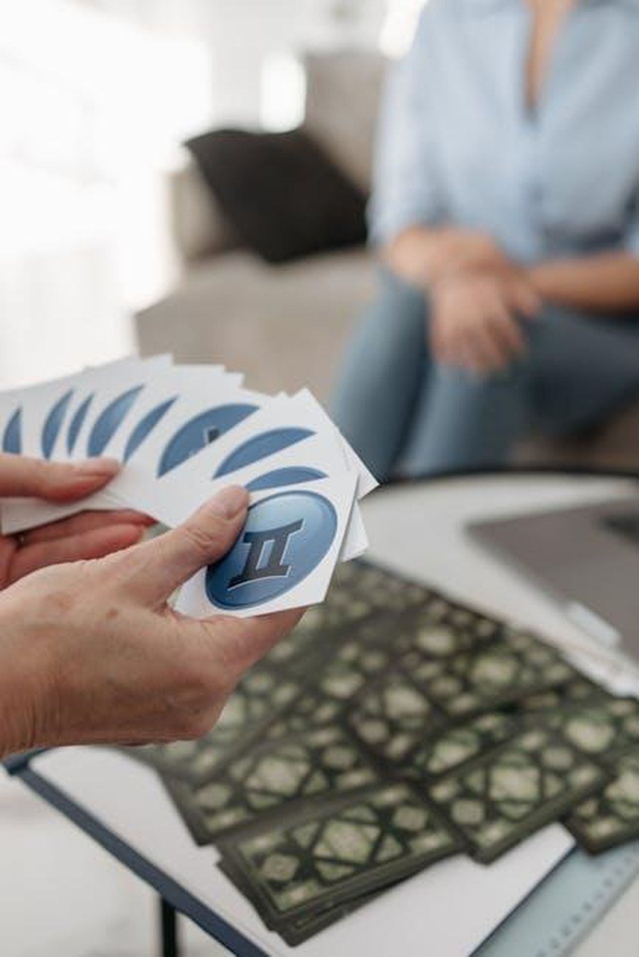Gemelli_risveglio_dei_sensi_e_opportunit_lavorative_1H5t4mR2gD - Confidenze24 Source: Pavel Danilyuk - pexels - A person holding Gemini cards during a tarot reading session indoors, suggesting astrology and mystery.