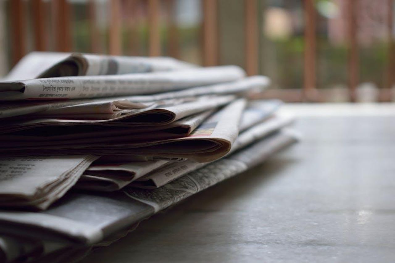 Gennaro__stanco_di_Michele_e_chiede_a_Roberto_di_liberarsi_del_giornalista_tDW8TfDr5v - Confidenze24 Source: brotiN biswaS - pexels - A close-up of a stack of newspapers resting on a desk, symbolizing information and media.