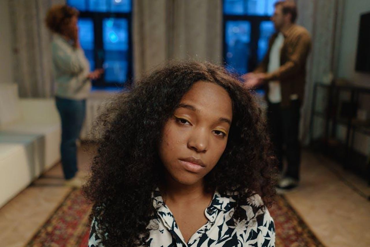 Gennaro_aggredisce_Vinicio_anticipazioni_Un_posto_al_sole_2428_febbraio_S9LOPGSwS8 - Confidenze24 Source: cottonbro studio - pexels - A teenage girl with curly hair looking concerned indoors with two adults in the background.