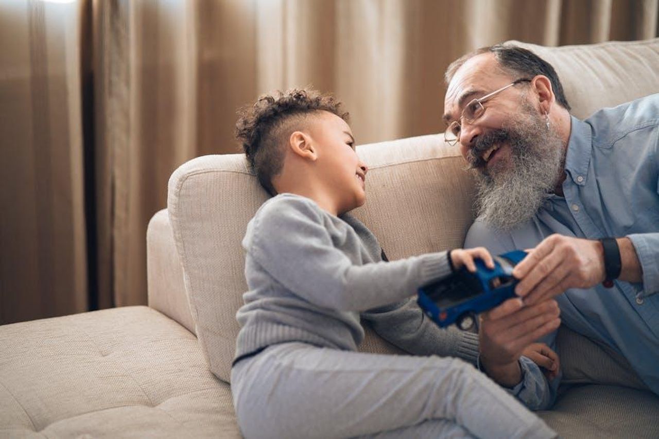 Gianmarco_dubita_sul_conto_di_Cristina_6L6WWlD8YO - Confidenze24 Source: Mikhail Nilov - pexels - A joyful grandfather and grandson sharing a playful moment on the couch, indoors.